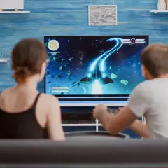 Para grająca w grę kosmiczną na dużym telewizorze.